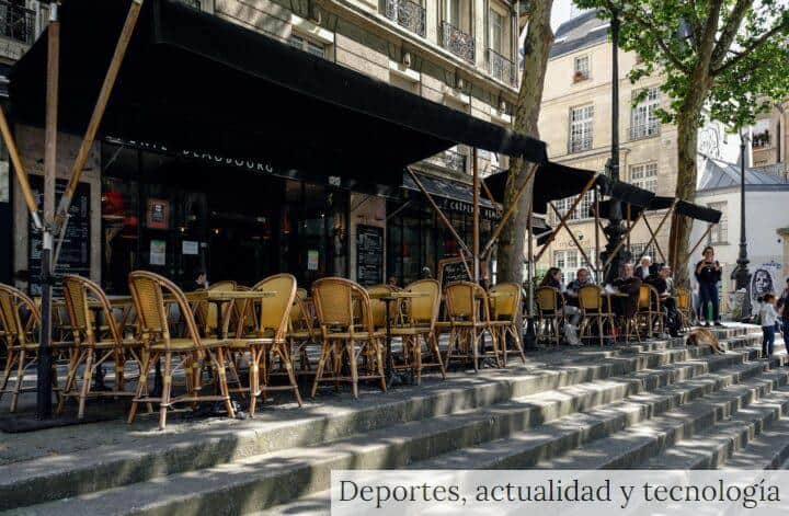 Outdoor Paris café with wicker chairs and people enjoying a sunny day on stone steps.